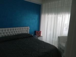 ein Schlafzimmer mit einem Bett, einer blauen Wand und einem Fenster in der Unterkunft Residence Acqua di Mare in Termoli