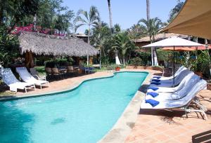 a swimming pool with lounge chairs and an umbrella at Hotel Casamar Suites in Puerto Escondido