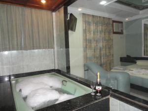 a bathroom with a bath tub with a bottle of wine at Hotel Premier (Adult Only) in Nilópolis