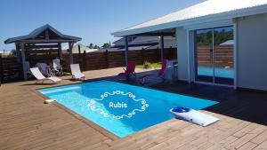 a swimming pool with chairs and a gazebo at Villa Rubis in Le Moule