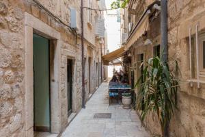 an alley in an old town with people sitting at tables at Sogaro in Dubrovnik