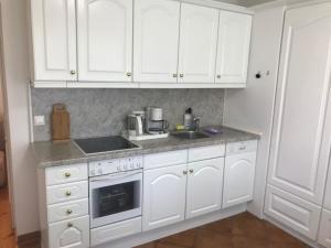 a white kitchen with white cabinets and a sink at Seeblick III in Bad Saarow