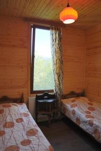 a bedroom with two beds and a window and a chair at Chateau Dio in Ambrolauri