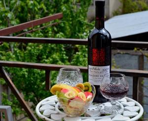a bottle of wine and a bowl of fruit on a table at Boutique Hotel Eco-House Tbilisi in Tbilisi City