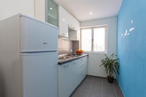 a small kitchen with a refrigerator and a sink at Apartments Vidulić in Mali Lošinj