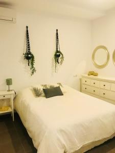 カディスにあるCasa de las Cinco Torresの白いベッドと壁に植物が飾られたベッドルーム1室が備わります。
