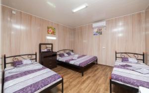 two beds in a room with wooden walls and wooden floors at Мини Отель Милый in Sanzhiyka