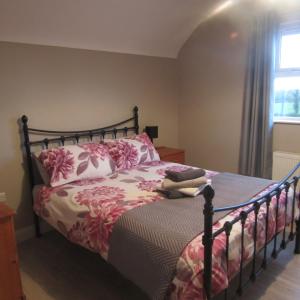1 dormitorio con 1 cama con sábanas rosas y blancas en Knockninny Barn at Upper Lough Erne, County Fermanagh, en Enniskillen