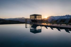 a pool of water with the sun setting behind mountains at Hotel Avelina in Avelengo +86 photos