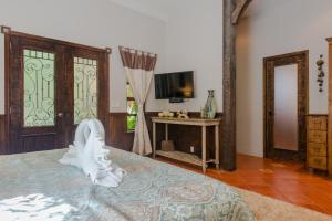 a bedroom with a bed and a tv and a table at Hacienda Xcaret in Playa del Carmen