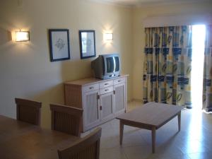 uma sala de estar com uma televisão num armário com uma mesa em Vila Marachique 304 2 bedroom em Alvor