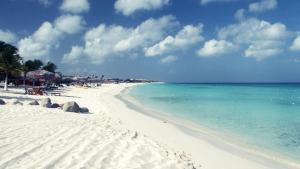uma praia branca com o oceano e pessoas nela em Buddha Studios Aruba em Palm-Eagle Beach