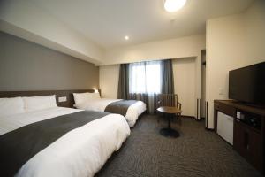 Postel nebo postele na pokoji v ubytování Dormy Inn Oita
