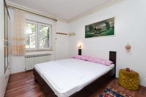 a bedroom with a white bed and a window at Apartments and Room Luka in Klenovica