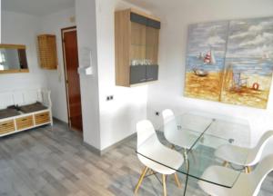 a dining room with a glass table and white chairs at Apartamento Malgrat de mar in Malgrat de Mar