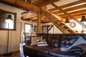 un sofá de cuero en una sala de estar con techos de madera. en Waterfall Cottage, en Sainte-Melanie