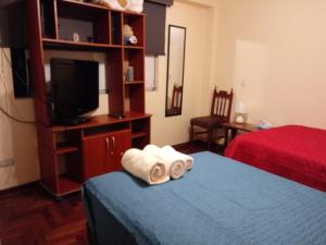 a bedroom with a bed and a television and towels at Casa Marite in Lima
