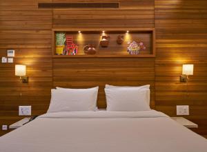 a bedroom with a large white bed with wooden walls at Hotel Atharv Top Rated Business Hotel in Kolhapur in Kolhapur