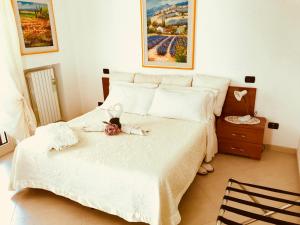 een slaapkamer met een wit bed met een pop erop bij Villa Aurora B&B in Bari