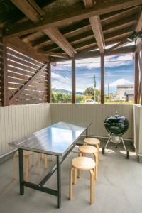 eine Terrasse mit einem Tisch, Stühlen und einem Grill in der Unterkunft Villa Yushin in Fujikawaguchiko