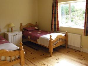 een slaapkamer met 2 aparte bedden en een raam bij Lough Currane Cottage in Waterville