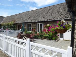een huisje met een wit hek en bloemen bij Rosemount Coach House in Ballycarney