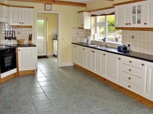 uma grande cozinha com armários brancos e piso em azulejo em Lough Currane Cottage em Waterville