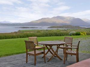 a wooden table and chairs with a view of a lake at Lough Currane Cottage in Waterville