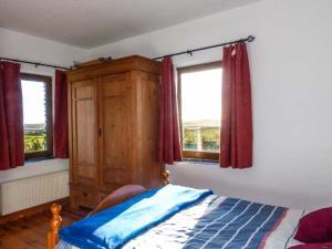 1 dormitorio con 1 cama y 2 ventanas en Corr an Droma en Rossbrin