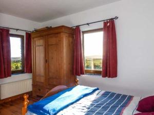 a bedroom with a bed and two windows at Corr an Droma in Rossbrin