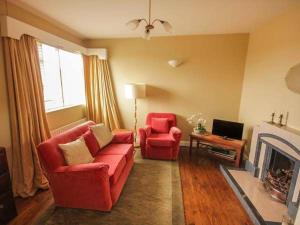 a living room with two red chairs and a fireplace at Teach Annie in Falcarragh