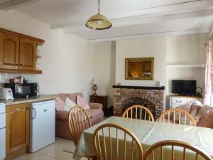 a kitchen and living room with a table and a fireplace at Brandy Harbour Cottage in Kilcolgan