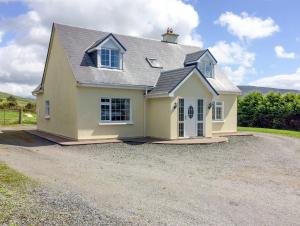 a large yellow house with a gravel driveway at The Slate House in Cahersiveen