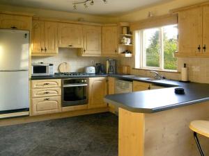 a kitchen with wooden cabinets and a white refrigerator at 19 River Glen in Curracloe