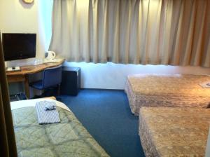 a hotel room with two beds and a desk at Asano Hotel in Kitakyushu