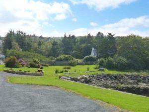 a park with a bench and a pond and trees at Quay Road Cottage in Dungloe