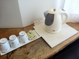 a tea kettle and four cups on a table at Asano Hotel in Kitakyushu