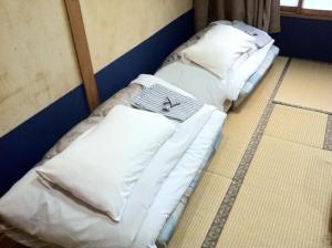 two beds in a room with white sheets and pillows at Asano Hotel in Kitakyushu