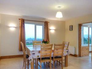 a dining room with a table and chairs and windows at Kerry Way Cottage in Coad