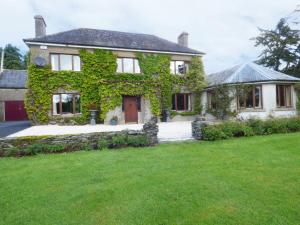 a house covered in green ivy with a yard at Maifield in Mullennaglogh