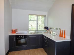 uma cozinha com armários pretos, um lavatório e uma janela em Hidden Gem Cabin em Dungloe
