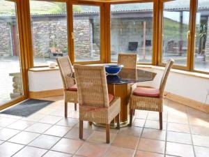 een eetkamer met een tafel, stoelen en ramen bij Finn House in Castlegregory