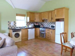 a kitchen with wooden cabinets and white appliances at The Bay in Caherdaniel