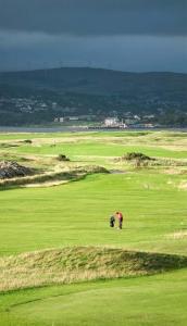 a person bending over on a green golf course at The Beach House Apartment in Buncrana