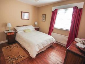 een slaapkamer met een bed en een raam met rode gordijnen bij Teach Annie in Falcarragh