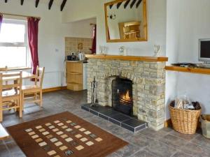 a living room with a stone fireplace and a dining room at Lully More Cottage in Doochary