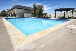 a swimming pool with blue water in front of a house at Kerang Valley Resort in Kerang