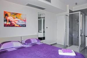 a bedroom with a purple bed and a painting on the wall at Villa Andrea in Elounda
