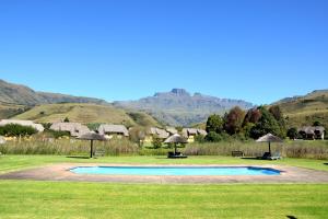 a swimming pool with umbrellas and mountains in the background at Champagne Haven - Chalet 6 Mount Champagne in Champagne Valley