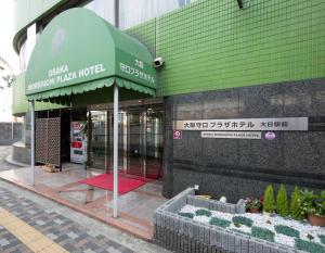 Osaka Moriguchi Plaza Hotel في أوساكا: متجر أمام مبنى به مظلة خضراء